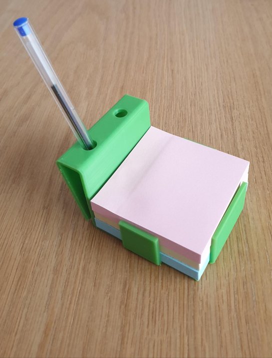 Support de post-it vert, avec un stylo posé sur une table